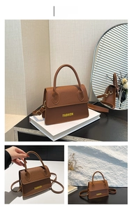 Detail of lychee textured brown leather handbag with fashion lettering and adjustable strap