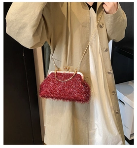 Detail of red plush shell bag with gold chain strap held by a model in a trench coat