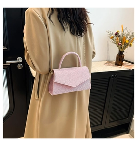 Détail d'un sac à main rose pailleté avec bandoulière chaîne et poignée sur modèle