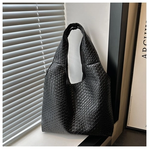 Macro detail of the black woven texture and broad handle on this soft leather tote bag