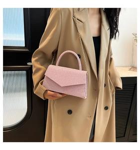 Detail of pink glitter square handbag featuring a metal chain strap and top handle