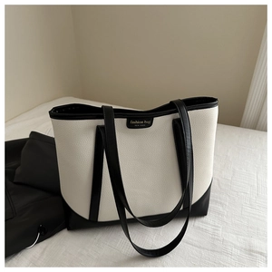 Macro shot of large black and white tote bag with lychee grain leather and gold letters