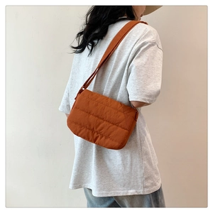 Detail of orange quilted puffy shoulder bag in nylon fabric with textured cross stitching