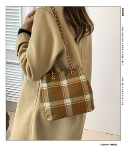 Detail of British style brown plaid woolen tote bag with a golden metal chain strap