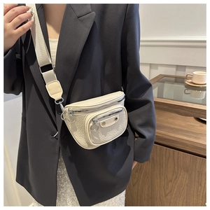 Detail of beige faux leather crossbody bag featuring wide strap and silver-tone hardware