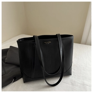 Close-up of black tote bag with lychee grain texture and gold fashion logo detail