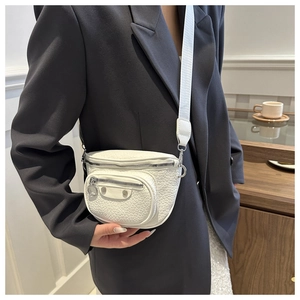 Detailed close-up of white crossbody bag with silver studs and adjustable wide strap
