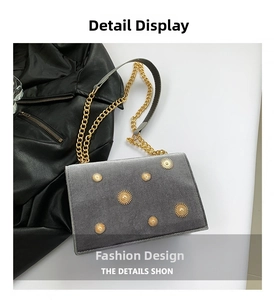 Close-up of grey velvet crossbody bag with golden sunburst rivets and chain strap