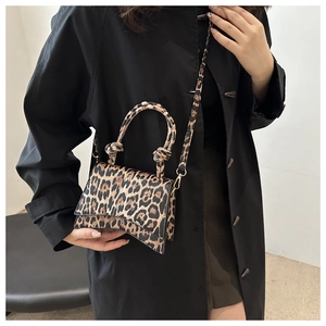 Detail of leopard print handbag with unique curved base and knotted handle accents