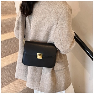Detail shot of black leather crossbody bag with gold metal square twist lock closure
