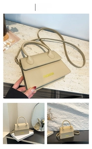 Macro detail of khaki litchi grain leather handbag with FASHION logo and handle strap