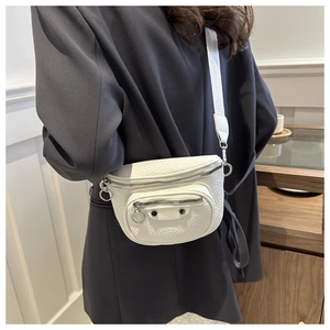 Detail of white lychee leather crossbody bag featuring metal rings and rivets with wide strap