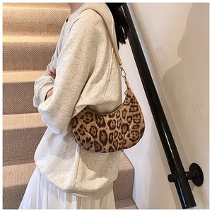 Detail of leopard print crescent bag with metal hardware and sleek shoulder strap