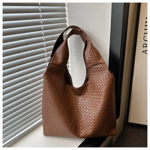 Close-up of brown woven leather texture on a soft shoulder tote bag with a wide strap