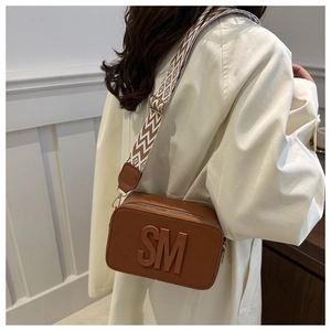 Detail of caramel leather camera bag with SM embossing and geometric wide strap