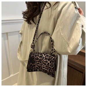 Detail of stylish leopard print crossbody bag with unique curved base and knotted handle