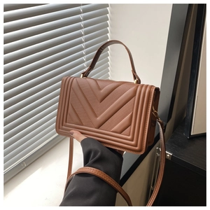 Detailed close-up of caramel brown handbag featuring unique V-quilted faux leather texture