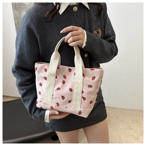 Détail du sac cabas en velours côtelé avec motif fraises rouges et poignée en toile crème