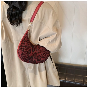 Close-up of leopard print burgundy velvet shoulder bag on a model side view