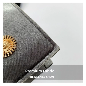 Detailed close-up of dark grey velvet fabric and sunburst gold metal embellishment