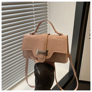 Close-up of small pink wrinkled patent leather handbag with silver buckle and handle