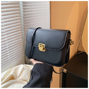 Detail of black faux leather crossbody bag with vintage gold square buckle closure