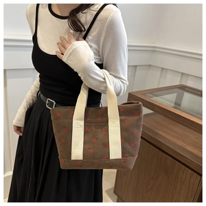 Détail du sac fourre-tout en velours marron avec broderie de fraises et anses beige