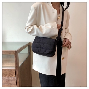Close-up of black quilted crossbody bag with adjustable wide strap on model