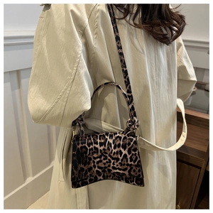 Detail view of the leopard print handbag showing the curved base and knotted handle texture