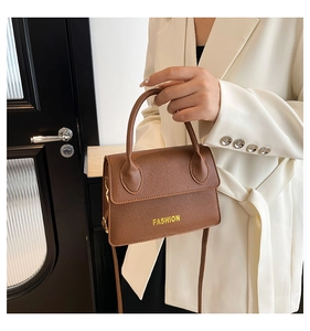 Detail of brown litchi pattern leather handbag with gold Fashion text and top handle