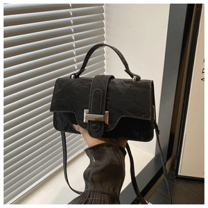 Detail of the black crinkled leather crossbody bag with silver buckle and handle