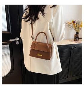 Detail view of brown lychee grain leather handbag with gold FASHION letter logo