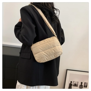 Detail of beige quilted shoulder bag with horizontal stitching on soft nylon fabric