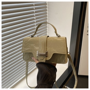 Close-up of light green glossy wrinkled leather handbag with silver metallic buckle detail