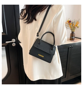 Black pebbled leather crossbody bag with yellow Fashion text detail worn by model