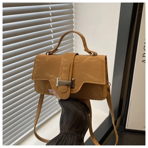 Detail of mustard yellow wrinkled leather handbag with a silver metal buckle closure
