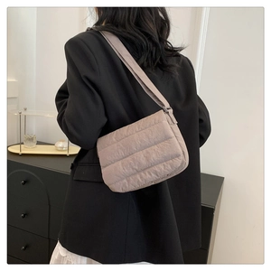 Detailed view of quilted square crossbody bag worn over a black blazer for styling