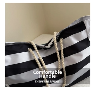Detail of nautical striped canvas tote bag featuring thick rope handles and silver eyelets
