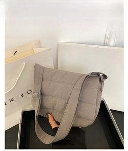 Detail of grey quilted cotton shoulder bag with soft padded texture and wide strap