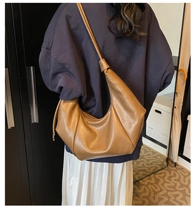 Detail of a brown PU leather half-moon hobo bag with a stylish knotted shoulder strap