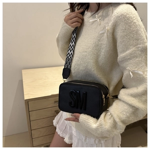 Detail of black camera bag with 3D SM logo and geometric pattern wide shoulder strap