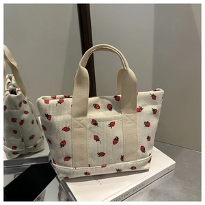 Détail du sac fourre-tout en velours côtelé blanc cassé avec broderies de fraises rouges