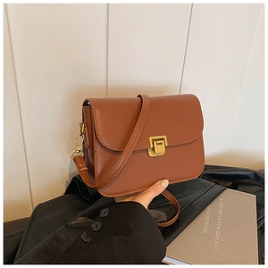 Detail of vintage brown PU leather crossbody bag with golden metal lock and strap