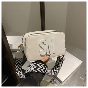 Close-up of white crossbody camera bag featuring SM logo and geometric wide strap