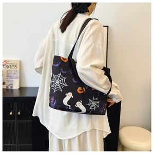 Detail of a black Halloween canvas tote bag with ghost and pumpkin patterns on a model