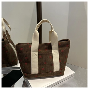 Détail du sac cabas en velours côtelé marron avec fraises rouges et anses crème