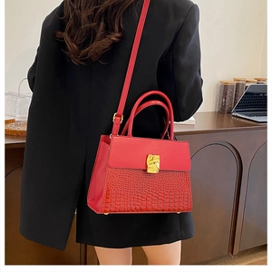 Detail view of red crocodile pattern shoulder bag with a gold geometric metal buckle