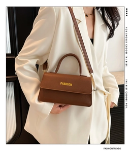 Detail of brown lychee grain leather handbag with Fashion text and top handle