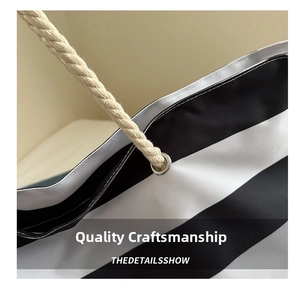 Detail of metal eyelets and thick cotton rope handles on a striped canvas tote bag