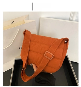 Detail of orange quilted nylon crossbody bag with adjustable strap and down texture